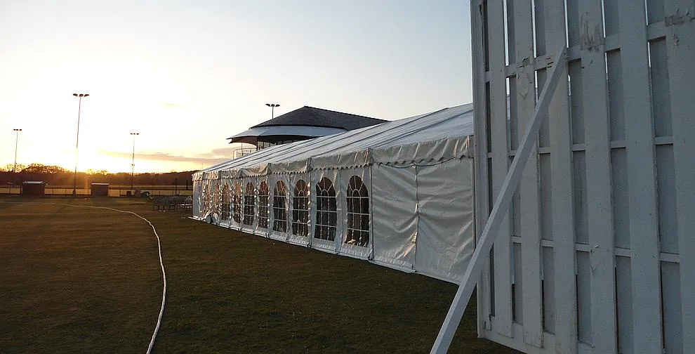 A framed marquee erected on hard standing next to a building