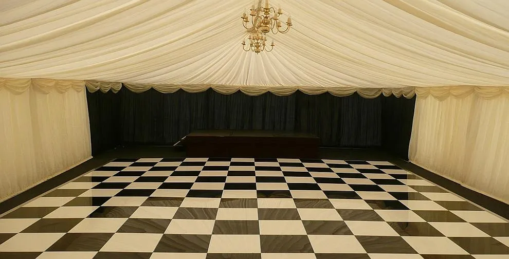 A black and white chequered dance floor laid inside a marquee