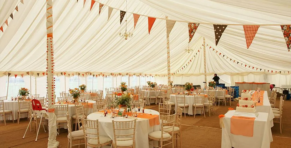 Inside a traditional marquee lined with bunting across the ceiling