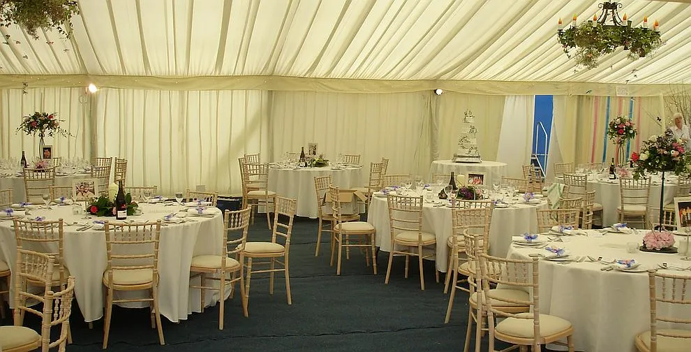 A framed marquee with clear window walls set up on a lawn
