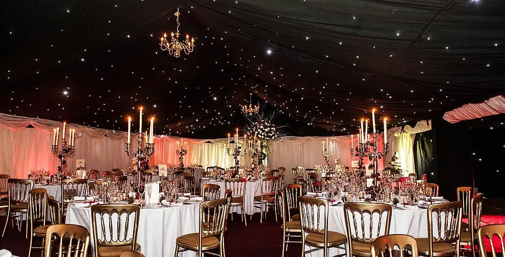 Tables and chairs set for dinner inside a lined marquee