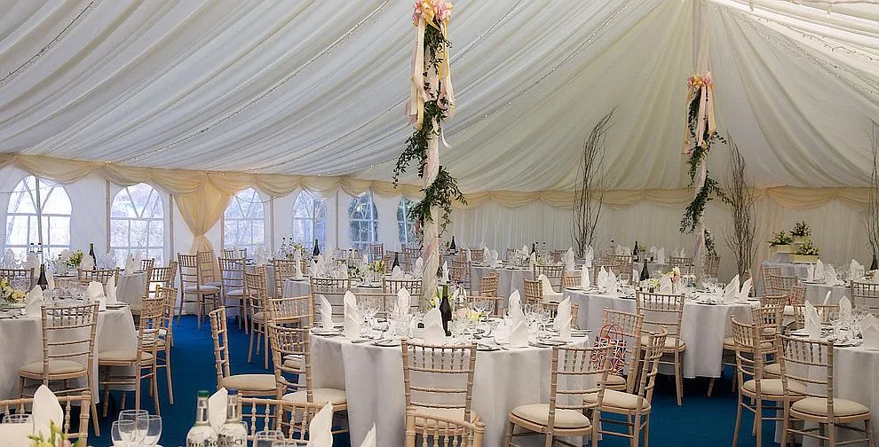 A traditional marquee laid up with round tables and centrepieces