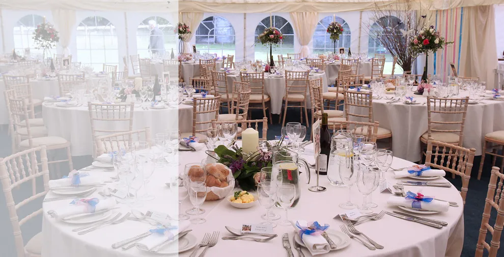 Round tables laid with glassware, linen and floral centrepieces inside a marquee
